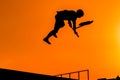 Teenager silhouette showing high jump tricks on scooter against orange sky Royalty Free Stock Photo