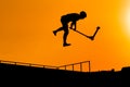 Teenager silhouette showing high jump tricks on scooter against orange sky Royalty Free Stock Photo