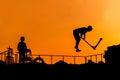 Teenager silhouette showing high jump tricks on scooter against orange sky Royalty Free Stock Photo