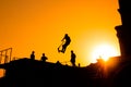 Teenager silhouette showing high jump tricks on scooter against orange sky Royalty Free Stock Photo