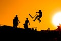 Teenager silhouette showing high jump tricks on scooter against sunset sky Royalty Free Stock Photo