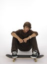 Teenager sitting with feet on skateboard