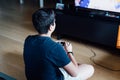 Teenager sitting on the floor at home playing a video game on the console Royalty Free Stock Photo