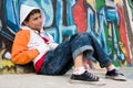 Teenager sitting near a graffiti wall Royalty Free Stock Photo