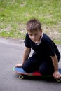 A teenager with a skateboard. Sits on a skateboard.