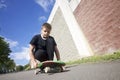 A teenager with a skateboard. Sits on a skateboard.