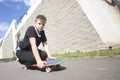 A teenager with a skateboard. Sits on a skateboard.