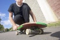 A teenager with a skateboard. Sits on a skateboard.