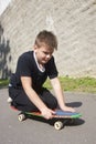 A teenager with a skateboard. Sits on a skateboard.