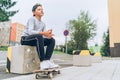 Teenager skateboarder boy portrait in a baseball cap with old skateboard on the city street. Youth generation Free time spending