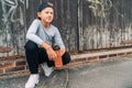 Teenager skateboarder boy sitting beside a wooden grunge graffiti wall with skateboard and Water bottle flask. Youth generation Royalty Free Stock Photo