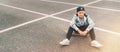 Teenager skateboarder boy with a skateboard sitting on asphalt playground and resting after he made tricks. Youth generation