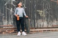 Teenager skateboarder boy standing beside a wooden grunge graffiti wall with skateboard and Water bottle flask. Youth generation