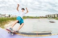 Teenager skater in a cap and shorts on rails on a skateboard in a skate park