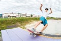 Teenager skater in a cap and shorts on rails on a skateboard in a skate park