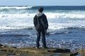 Teenager with skaterboard watching waves Royalty Free Stock Photo