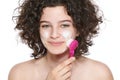 Teenager skincare. Beautiful teenage girl with gorgeous curly hair using face brush and foaming cleanser. Face washing concept.