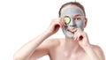 Teenager skincare concept. Young teen girl with dry clay facial mask holding two slices of cucumber Royalty Free Stock Photo