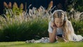 A teenager with a smartphone and headphones lies on the grass in the park Royalty Free Stock Photo