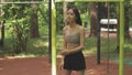 Teenager sports summer activities, the girl does sports exercises outdoor, the athlete does inclines in the street gym