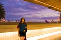 Teenager standing at Hawaiian airport before evening flight , colorful skies