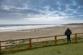 Teenager standing by wooden barrier and looking at beautiful Fanore beach. Ireland. Blue cloudy sky and Atlantic ocean. Travel and