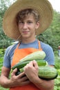 Teenager in straw hat holding zucchini