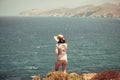 Teenager with straw hat standing on a cliff