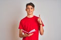 Teenager student boy reading a book over isolated background surprised with an idea or question pointing finger with happy face, Royalty Free Stock Photo