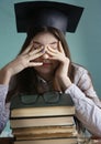 Teenager student girl in graduation cap with bood pile tired eyes Royalty Free Stock Photo