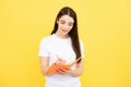 Teenager student girl isolated on yellow background. Cheerful young woman student in shirt hold notebooks showing. High Royalty Free Stock Photo