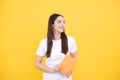 Teenager student girl isolated on yellow background. Cheerful young woman student in shirt hold notebooks showing. High Royalty Free Stock Photo