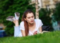 Teenager student girl lying on grass in park near university reading book outdoors Royalty Free Stock Photo