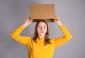 Teenager student girl taking cardboard box off her head having bright idea or plan. Royalty Free Stock Photo