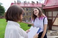 Teenager student girl talking with teacher, woman with clipboard