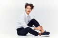 a teenager in a suit and sneakers sits on the floor In a bright room side view Royalty Free Stock Photo
