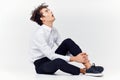 a teenager in a suit and sneakers sits on the floor In a bright room side view Royalty Free Stock Photo