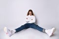 Teenager in sunglasses, jeans, sweater, socks and sneakers. Posing sitting on floor, legs wide apart, isolated on white. Close up Royalty Free Stock Photo