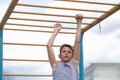 A teenager in a T-shirt is engaged in gymnastics on a horizontal bar