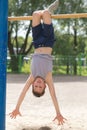 A teenager in a T-shirt is engaged in gymnastics on a horizontal bar