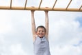 A teenager in a T-shirt is engaged in gymnastics on a horizontal bar