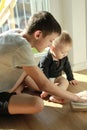 A teenager teaches his younger brother a toddler by showing a book.