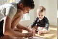 A teenager teaches his younger brother a toddler by showing a book.