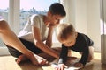 A teenager teaches his younger brother a toddler by showing a book.