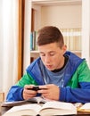 Teenager texting with smartphone while studying Royalty Free Stock Photo