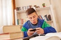 Teenager texting with smartphone while studying Royalty Free Stock Photo