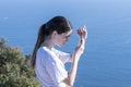 Teenager on top Mount Maunganui checking device while shading screen