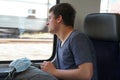 A teenager on train with his rucksack and facial mask prepared for use if needed