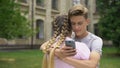 Teenager using cell phone while hugging boyfriend, absorbed by social networks