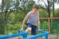 The teenager in a vest is engaged on uneven bars